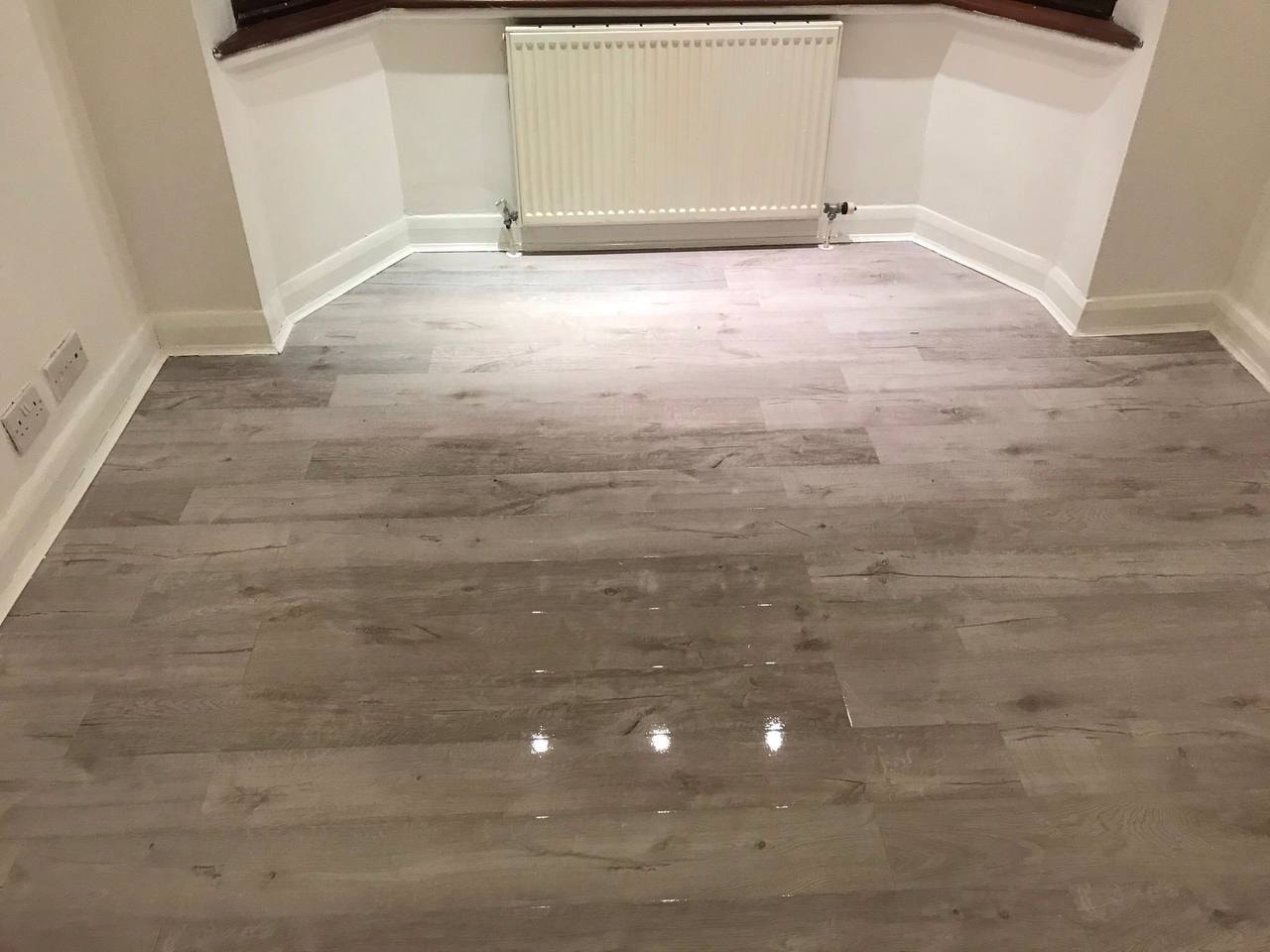 Grey wood-effect laminate flooring in bay window room — West London